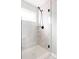 Modern walk-in shower featuring white marble-style tile, a glass enclosure, and sleek black fixtures at 10025 E 63Rd Ave, Denver, CO 80238