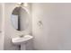 Half bath featuring a pedestal sink, an oval mirror, and modern fixtures at 20861 E 40Th Ave, Denver, CO 80249
