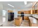 Bright kitchen featuring a central island, black appliances, and warm-toned oak cabinetry at 20861 E 40Th Ave, Denver, CO 80249