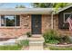 Close-up of a brick home's entrance featuring a dark front door, address numbers, and plants at 11433 Carlile St, Northglenn, CO 80233