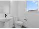 Bright powder room with a pedestal sink, toilet and a large window letting in natural light at 14281 Currant St, Broomfield, CO 80020