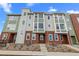 Modern townhome with brick accents and a blend of neutral gray and green siding, set against a bright blue sky at 14281 Currant St, Broomfield, CO 80020