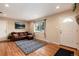 Inviting living room featuring hardwood floors, a decorative rug, and a cozy leather sofa at 11398 W Ford Pl, Lakewood, CO 80226