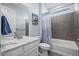 Well-lit bathroom features a tub and shower with a gray tiled wall and marble countertop vanity at 15604 Xenia Way, Brighton, CO 80602
