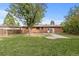 Brick home with grass, mature shade tree, and concrete patio at 5463 Shoshone St, Denver, CO 80221