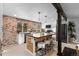 Renovated kitchen with an island, seating, white cabinetry, a brick accent wall and stainless steel appliances at 5463 Shoshone St, Denver, CO 80221