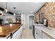 Stylish kitchen showcases a wood island, farmhouse sink, brick accent wall, and wood look tiled flooring at 5463 Shoshone St, Denver, CO 80221