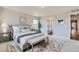 Bright bedroom features a Queen bed, a bench, and a view into the attached bathroom at 5975 Hanover St, Denver, CO 80238