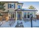 Two-story townhome with stone and siding exterior, snowy landscaping, and a covered entryway at 11261 W Quincy Pl, Littleton, CO 80127