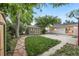 A nicely landscaped backyard with mature trees, a shed, and a stone walkway at 5515 Dudley Ct, Arvada, CO 80002