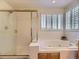 Bright bathroom showcasing a glass-enclosed shower, large soaking tub, and shuttered window for natural light at 10904 Eagle Run Dr, Parker, CO 80138