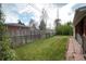 Fenced backyard featuring green lawn, brick patio and detached storage with mature trees under a partly cloudy sky at 5582 E Colorado Ave, Denver, CO 80222