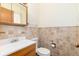Bathroom featuring tiled walls, vanity with sink, and a toilet, offering a functional space at 5582 E Colorado Ave, Denver, CO 80222