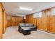 Spacious basement living area with wood paneled walls and neutral carpet at 5700 E Floyd Ave, Denver, CO 80222