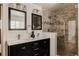 Modern bathroom featuring double sinks, stone tile shower, and black cabinetry at 5700 E Floyd Ave, Denver, CO 80222