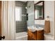 Bathroom with gray tiles, shower, wooden vanity and a mirror at 5700 E Floyd Ave, Denver, CO 80222