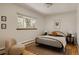 Cozy bedroom featuring a metal-frame bed, wood floors, and light-filled windows at 5700 E Floyd Ave, Denver, CO 80222