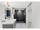 Modern bathroom featuring a sleek vanity with illuminated mirror and walk-in shower with black textured tiling and blue-tiled flooring at 1232 Berganot Trl, Castle Pines, CO 80108