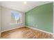 Bright, unfurnished bedroom with a large window and hardwood floors, painted with one green accent wall at 1232 Berganot Trl, Castle Pines, CO 80108