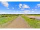 Gravel trail winding through a green park landscape under a clear blue sky with scattered clouds at 1232 Berganot Trl, Castle Pines, CO 80108