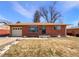 Charming brick home featuring an attached garage, landscaped yard, and classic architectural details at 3268 S Patton Ct, Denver, CO 80236