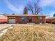 Charming brick home featuring an attached garage, landscaped yard, and classic architectural details at 3268 S Patton Ct, Denver, CO 80236