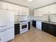 Kitchen featuring white appliances, white cabinets, dark lower cabinets, and tile flooring at 3268 S Patton Ct, Denver, CO 80236