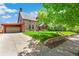 Angle shot of a stone house with an attached garage and beautiful greenery at 3520 Newton St, Denver, CO 80211
