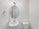Powder room featuring pedestal sink, oval mirror, updated lighting, and toilet at 4670 Quandary Peak St, Brighton, CO 80601