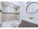 Updated bathroom featuring a vanity, toilet, and tub with tile surround at 118 S Yates Way, Denver, CO 80219