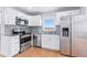 Modern kitchen with stainless steel appliances, white cabinetry, granite countertops, and hardwood floors at 118 S Yates Way, Denver, CO 80219
