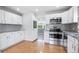 Well-lit kitchen featuring stainless steel appliances, white cabinets, light countertops and hardwood floors at 118 S Yates Way, Denver, CO 80219