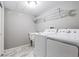 Functional laundry room featuring a new washer and dryer, utility sink, and marble floors at 118 S Yates Way, Denver, CO 80219