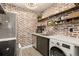 Cozy kitchen features brick wall, stainless appliances, open shelving, and integrated washer/dryer at 3035 Oneal Pkwy # 36T, Boulder, CO 80301