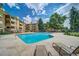 A community pool with a stone patio, sun loungers, and mature trees in the background at 3035 Oneal Pkwy # 36T, Boulder, CO 80301