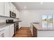 White kitchen features stainless steel appliances, granite countertops, and a sliding glass door to the backyard at 4730 Hatcher Dr, Brighton, CO 80601