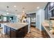 Open concept kitchen with large island, stainless steel appliances, hanging pot rack and wood flooring at 7514 Blue Water Dr, Castle Rock, CO 80108