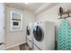 Bright laundry room with front loading washer and dryer, ironing board and decor at 7514 Blue Water Dr, Castle Rock, CO 80108