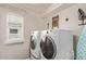 Well-lit laundry room with a washing machine, dryer, window, and laundry-themed wall decor at 7514 Blue Water Dr, Castle Rock, CO 80108