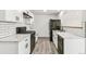Modern kitchen with white cabinets, marble countertops, black appliances, and wood-look floors at 180 W 78Th Pl, Denver, CO 80221