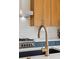 Close-up of the kitchen sink with gold hardware, white countertops, and stainless appliances at 2244 S Lincoln St, Denver, CO 80210