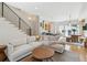 Open concept living room features a modern staircase, white couch, and seamless transition to the kitchen and dining area at 2244 S Lincoln St, Denver, CO 80210