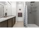 Well-lit bathroom featuring double sinks, granite countertops, modern shower with glass shelving, and neutral-colored tile flooring at 2578 Gray Wolf Pl, Castle Rock, CO 80104