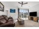 Bright living room with a brown sofa, ceiling fan, and a large sliding glass door at 2578 Gray Wolf Pl, Castle Rock, CO 80104