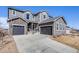 Charming two-story home with gray siding, stone accents, and a spacious three-car garage at 671 Green Mountain Dr, Erie, CO 80516