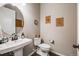 Powder room features a pedestal sink, toilet, wood floors, and decorative wall art at 671 Green Mountain Dr, Erie, CO 80516