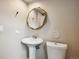 Bathroom with pedestal sink, gold-trimmed octagonal mirror, and toilet with funny sign at 7035 S Flower Ct, Littleton, CO 80128