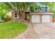 Charming front yard with well-maintained lawn, a brick facade, and a two-car garage providing curb appeal at 7035 S Flower Ct, Littleton, CO 80128