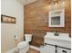 Modern bathroom features wood wall paneling, a toilet, vanity, and a stylish mirror at 23713 E Eads Dr, Aurora, CO 80016