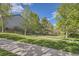 Expansive backyard with a well-maintained lawn, mature trees, and a winding sidewalk at 5316 S Rome St, Aurora, CO 80015